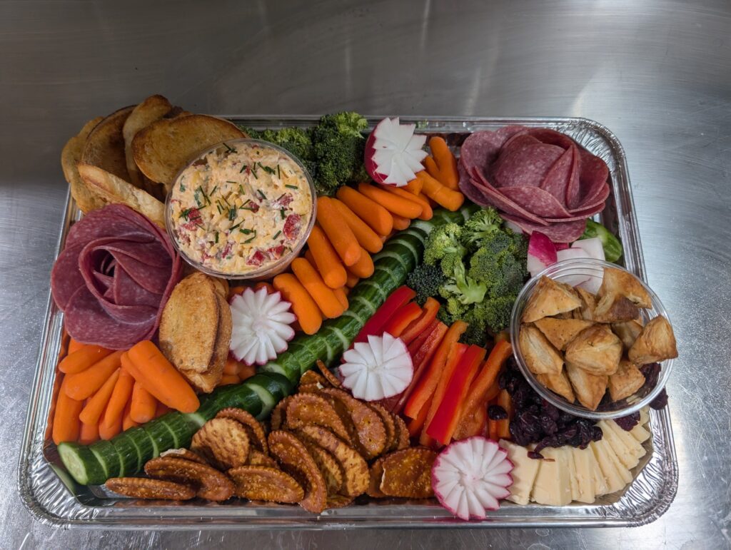 Charcuterie and vegetable tray with salami roses, pimento cheese, crostini, and carved radishes