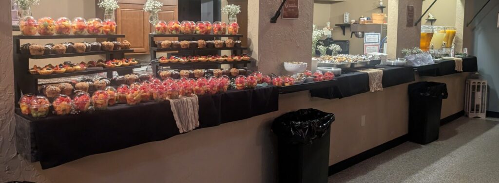Catered breakfast spread with fruit cups, muffins, and fruit tarts